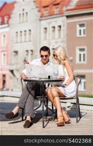 summer holidays, dating and tourism concept - couple with map in cafe in the city