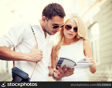 summer holidays, dating and tourism concept - couple with tourist book in the city