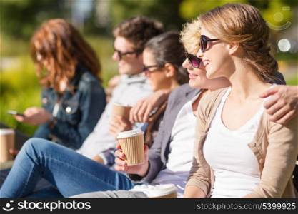 summer holidays, education, campus and teenage concept - group of students or teenagers with takeaway coffee cups hanging out