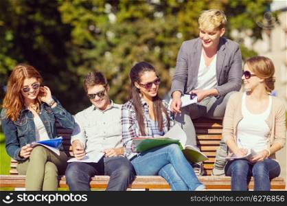 summer holidays, education, campus and teenage concept - group of students or teenagers with books, notebooks, files and folders