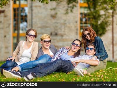 summer holidays, education, campus and teenage concept - group of students or teenagers hanging out outdoors
