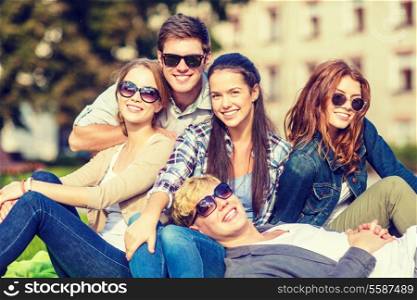 summer holidays, education, campus and teenage concept - group of students or teenagers hanging out outdoors