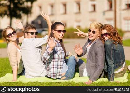 summer holidays, education, campus and teenage concept - group of students or teenagers waving hands