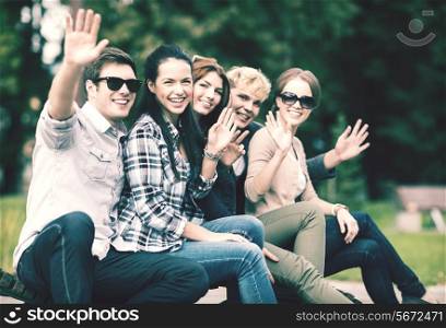 summer holidays, education, campus and teenage concept - group of students or teenagers waving hands