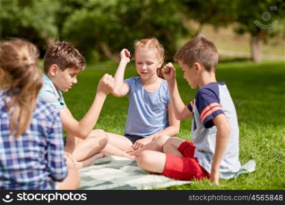 summer holidays, entertainment, childhood, leisure and people concept - group of happy pre-teen kids playing rock-paper-scissors game in park