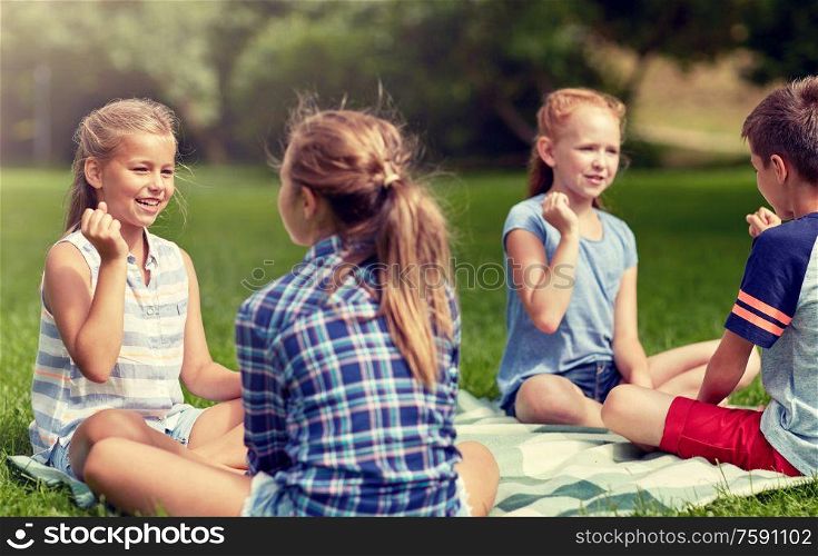 summer holidays, entertainment, childhood, leisure and people concept - group of happy pre-teen kids playing rock-paper-scissors game in park. happy kids playing rock-paper-scissors game