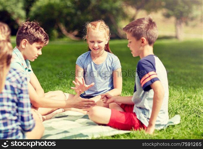 summer holidays, entertainment, childhood, leisure and people concept - group of happy pre-teen kids playing rock-paper-scissors game in park. happy kids playing rock-paper-scissors game