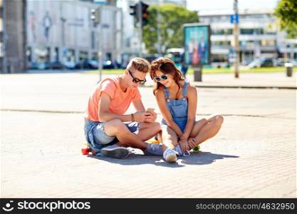 summer holidays, extreme sport and people concept - happy teenage couple with short modern cruiser skateboards on city street with smartphone