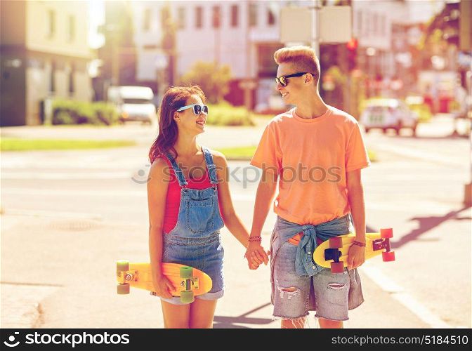 summer holidays, extreme sport and people concept - happy teenage couple with short modern cruiser skateboards on city street. teenage couple with skateboards on city street