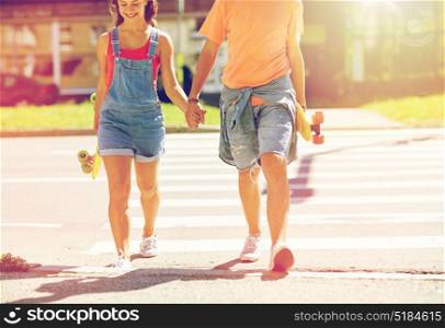 summer holidays, extreme sport, relations and people concept - happy teenage couple with short modern cruiser skateboards crossing city crosswalk. teenage couple with skateboards at city crosswalk