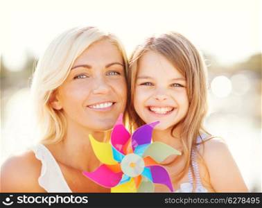 summer holidays, family, children and people concept - happy mother and child girl with pinwheel toy