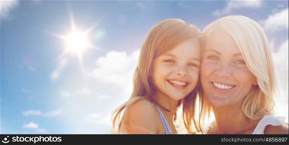summer holidays, family, children and people concept - happy mother and girl over sun in blue sky background