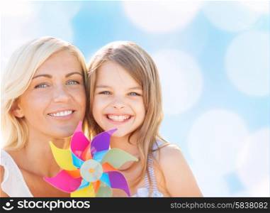 summer holidays, family, children and people concept - happy mother and girl with pinwheel toy over blue lights background