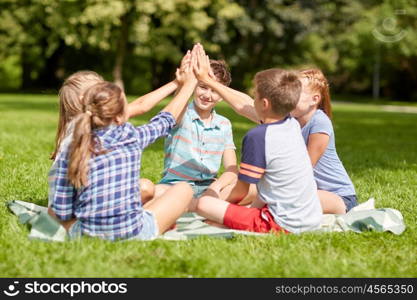 summer holidays, friendship, childhood, leisure and people concept - group of happy pre-teen kids making high five gesture in park