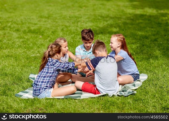 summer holidays, friendship, childhood, leisure and people concept - group of happy pre-teen kids putting hands together in park