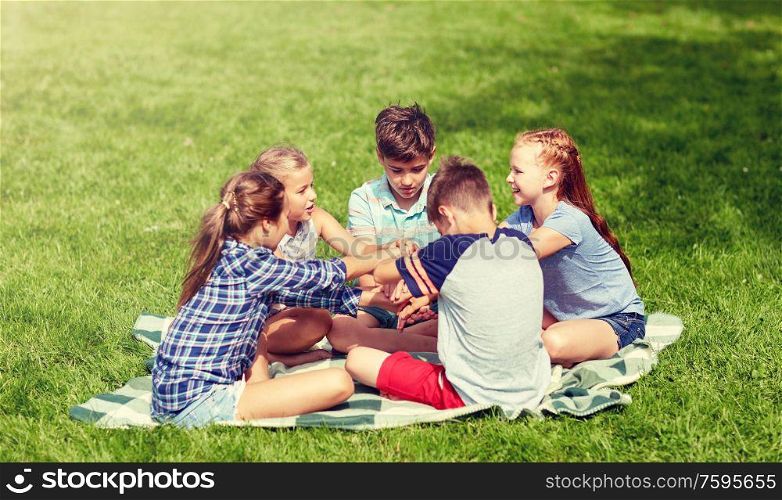 summer holidays, friendship, childhood, leisure and people concept - group of happy pre-teen kids putting hands together in park. group of happy kids putting hands together