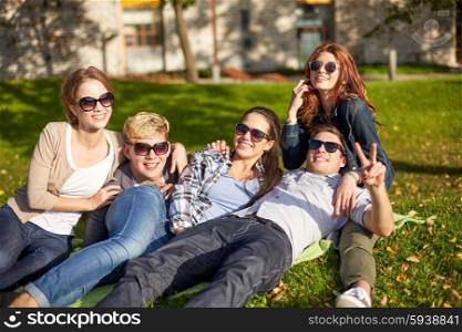 summer holidays, friendship, leisure and teenage concept - group of students or teenagers hanging out and showing victory gesture at campus or park