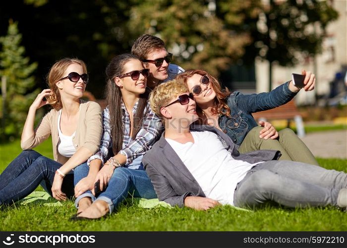 summer holidays, friendship, people and technology concept - group of happy teenagers taking selfie with smartphone