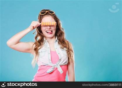 Summer holidays happiness concept. Happy joyful and cheerful young woman female model covering eyes with popsicle ice pop on blue background