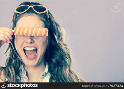 Summer holidays happiness concept. Happy joyful and cheerful young woman female model covering eyes with popsicle ice pop cross filter