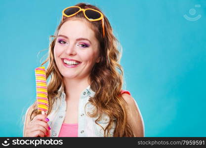 Summer holidays happiness concept. Happy joyful and cheerful young woman female model eating popsicle ice pop on blue background