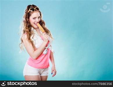 Summer holidays happiness concept. Happy joyful and cheerful young woman female model eating popsicle ice pop on blue background