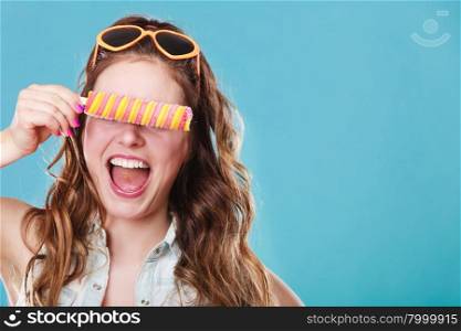 Summer holidays happiness concept. Happy joyful and cheerful young woman female model covering eyes with popsicle ice pop on blue background
