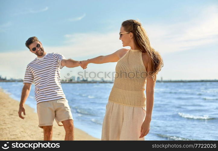 summer holidays, leisure and people concept - happy couple walking along beach. happy couple walking along summer beach