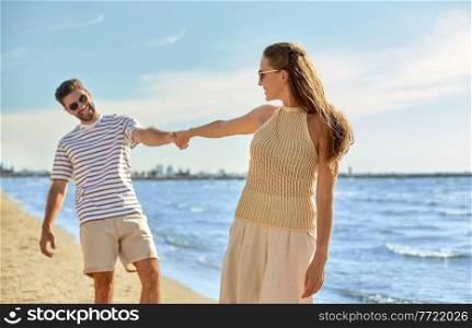 summer holidays, leisure and people concept - happy couple walking along beach. happy couple walking along summer beach