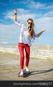 summer holidays, leisure and teenage concept - smiling teenage girl in sunglasses riding skate outside