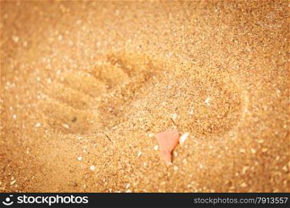 Summer holidays leisure concept. Footprint in golden sand on the shore of the sea