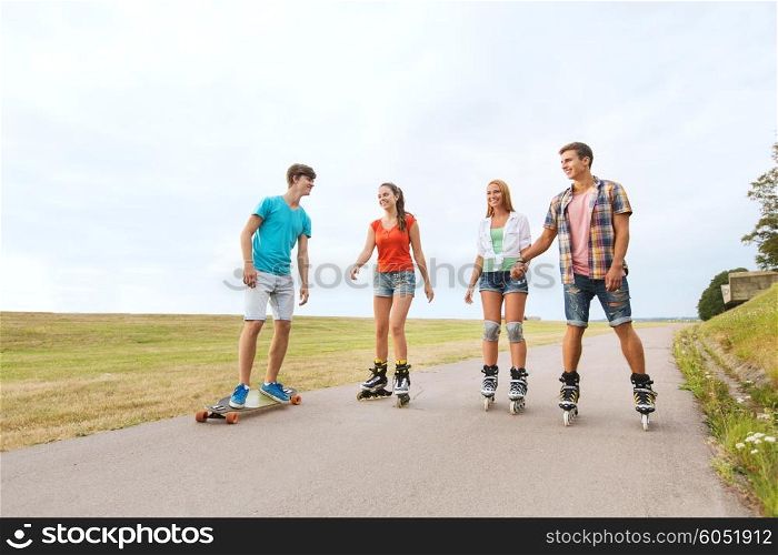 summer holidays, leisure, sport, love and people concept - group of happy teenage friends with rollerblades and longboards