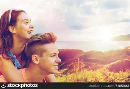 summer holidays, love and people concept - happy smiling teenage couple having fun over island and sea background. happy teenage couple having fun outdoors
