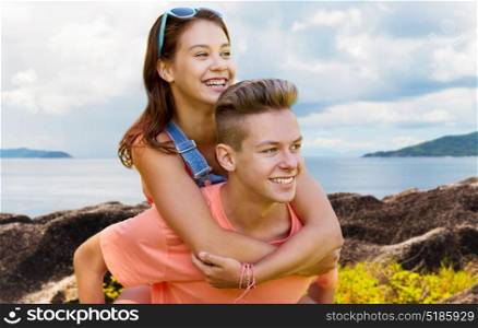 summer holidays, love and people concept - happy smiling teenage couple having fun over island and sea background. happy teenage couple having fun outdoors