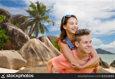 summer holidays, love and people concept - happy smiling teenage couple having fun over exotic seychelles beach background. happy teenage couple having fun on summer beach