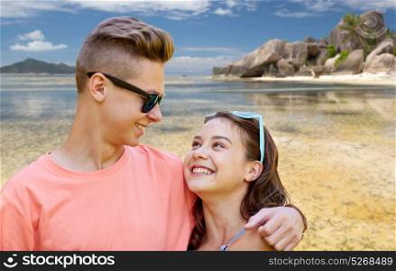 summer holidays, love and people concept - happy smiling teenage couple hugging over exotic seychelles beach background. happy teenage couple hugging at summer beach