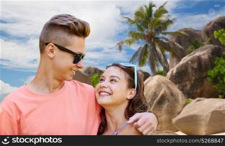 summer holidays, love and people concept - happy smiling teenage couple hugging over exotic seychelles beach background. happy teenage couple hugging at summer beach