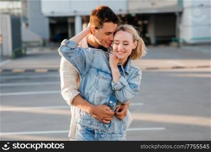 summer holidays, love and people concept - happy young couple hugging on city parking. happy young couple hugging on city parking