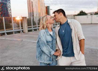 summer holidays, love and people concept - happy young couple hugging on roof top city parking. happy young couple on roof top city parking