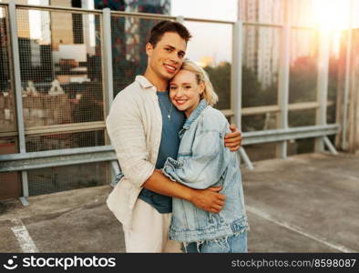 summer holidays, love and people concept - happy young couple hugging on roof top city parking. happy couple hugging on roof top city parking