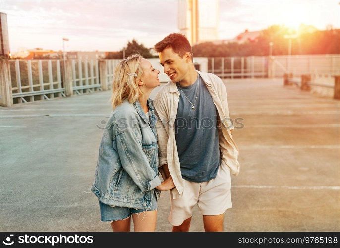 summer holidays, love and people concept - happy young couple hugging on roof top city parking. happy young couple on roof top city parking