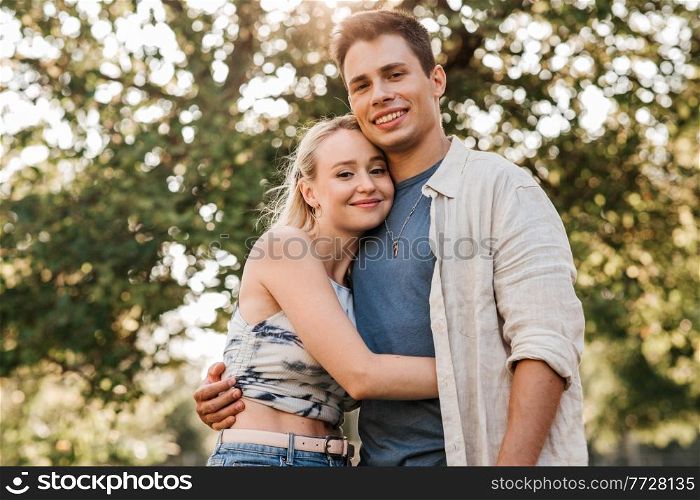 summer holidays, love and people concept - happy young couple hugging outdoors. happy young couple hugging outdoors