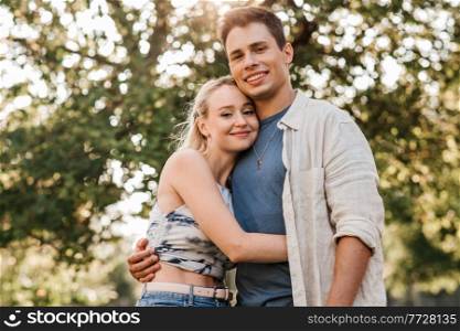 summer holidays, love and people concept - happy young couple hugging outdoors. happy young couple hugging outdoors