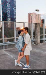 summer holidays, love and people concept - happy young couple kissing on roof top city parking. happy couple kissing on roof top city parking