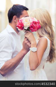 summer holidays, love, relationship and dating concept - couple with bouquet of flowers in the city