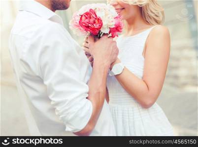 summer holidays, love, relationship and dating concept - couple with bouquet of flowers in the city