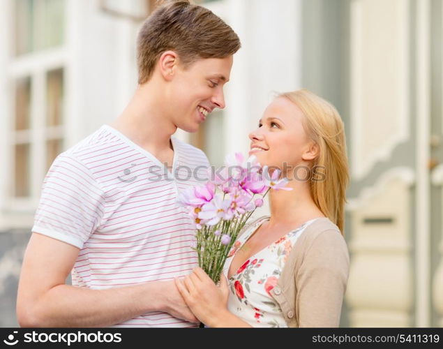 summer holidays, love, relationship and dating concept - couple with bouquet of flowers in the city