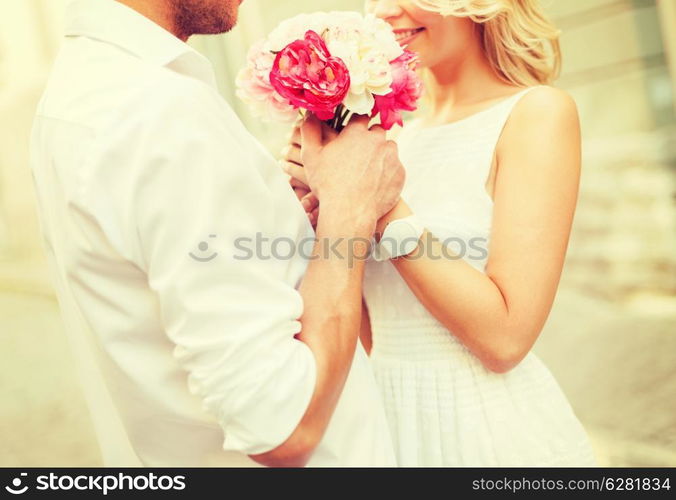 summer holidays, love, relationship and dating concept - couple with bouquet of flowers in the city