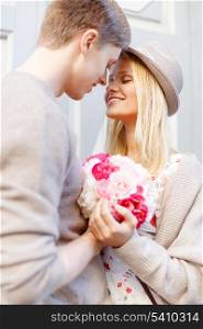 summer holidays, love, relationship and dating concept - happy couple with bouquet of flowers in the city