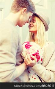 summer holidays, love, relationship and dating concept - happy couple with bouquet of flowers in the city